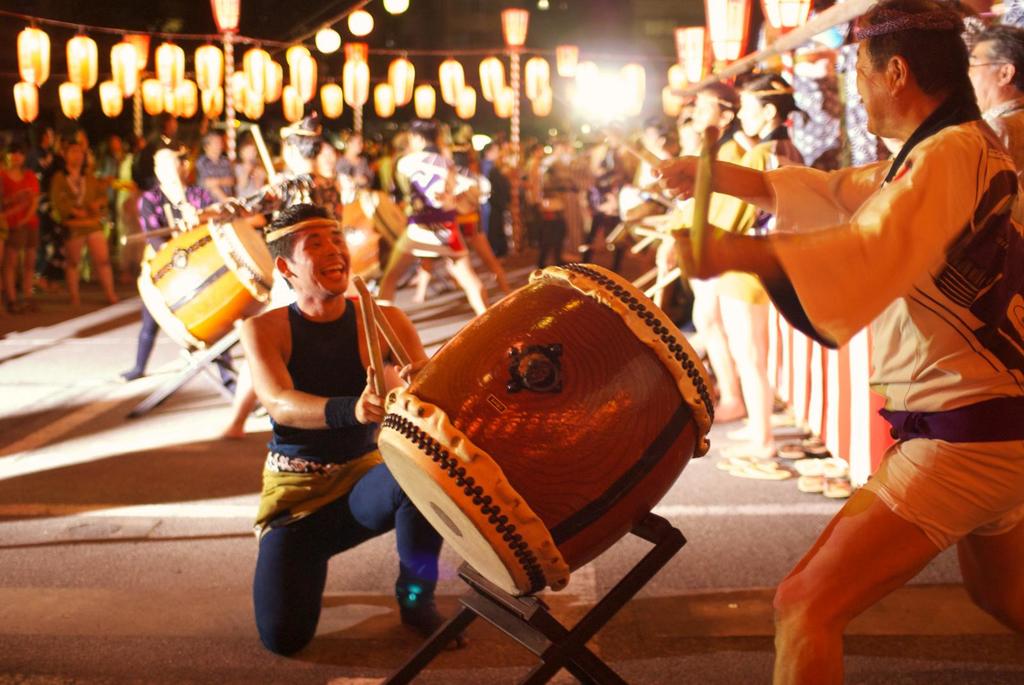 Männer spielen Trommel am Festival mit Lichtern darüber.