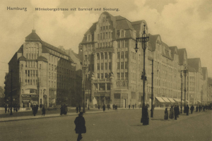 Schwarzes und weißes Foto einer Straßen Szene in Hamburg, Deutschland, mit Fußgängern, Gebäuden, Straßenmasten, Laternen und Fahrzeugen unter einem bewölkten Himmel.