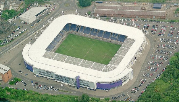 Aerial view of a soccer stadium in a city, surrounded by buildings, trees, and roads with vehicles, home of Tottenham Hotspur Football Club.