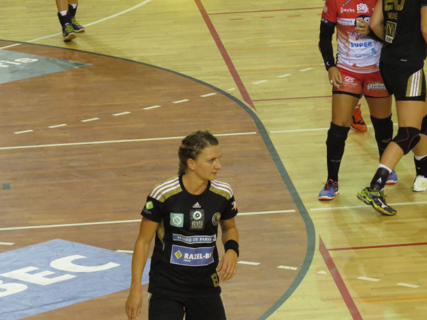 Eine Gruppe von Frauen in Sportuniformen spielt Handball auf einem Platz.
