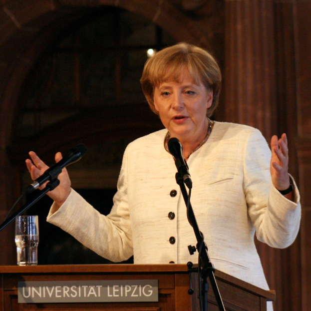 Bundeskanzlerin Angela Merkel bei einer Rede an einem Podium mit Mikrofon und einem Glas Wasser an der Universität Leipzig.