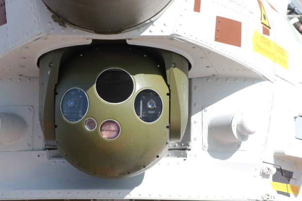 Nahaufnahme eines Militärfahrzeugs mit einer runden, grün-weißen Rakete, die seitlich an einem Metallrahmen montiert ist.