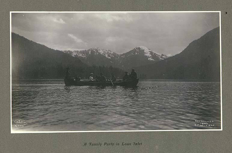 Schwarz-weiß-Foto einer Familie in einem Kanu auf einem See mit Bergen und Bäumen im Hintergrund, Himmel oben sichtbar und Text unten.