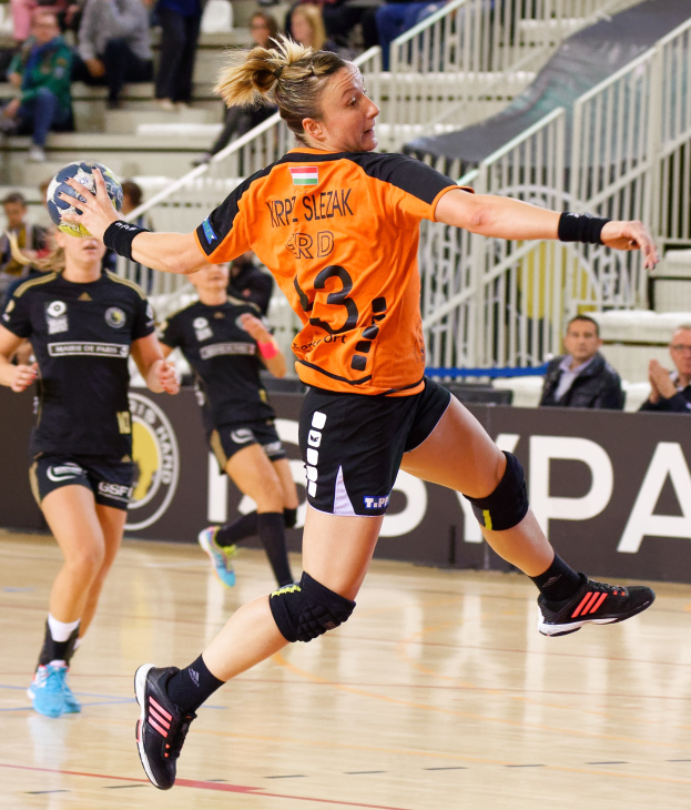 Eine Frau in einem orangen T-Shirt und schwarzen Shorts hält einen Handball, mit Zuschauern im Hintergrund während des "Krp Slezak - Handball-Weltmeisterschaft 2019".