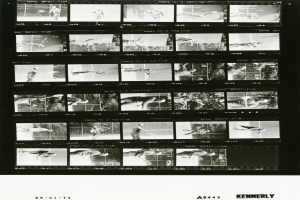 Schwarzes und weißes Foto eines Mannes in einem weißen Hemd und Shorts, der Tennis spielt und einen konzentrierten Gesichtsausdruck hat, mit einem Filmstreifen im Hintergrund.