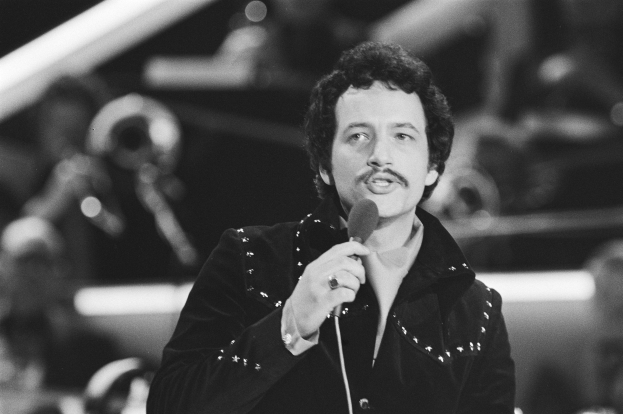 Elvis Presley in einem Schwarz-Weiß-Foto hält ein Mikrofon während einer Live-Aufführung, mit einem unscharfen Hintergrund.