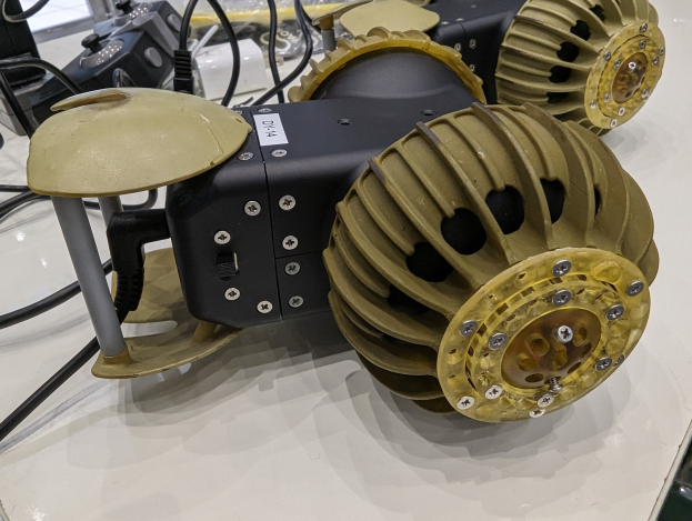 Nahaufnahme eines schlanken, metallischen 3D-gedruckten Roboters auf einem Tisch umgeben von Drähten.