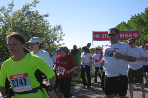 Eine Gruppe von Kindern, die bei einem Marathonlauf rennen, mit einer roten Fahne und Bäumen im Hintergrund.