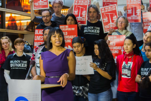 Aktivistin der Black-Lives-Matter-Bewegung spricht vor einer Menge mit Transparenten, Mikrofon und Schildern.