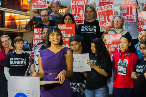 Aktivistin der Black-Lives-Matter-Bewegung spricht vor einer Menge mit Transparenten, Mikrofon und Schildern.