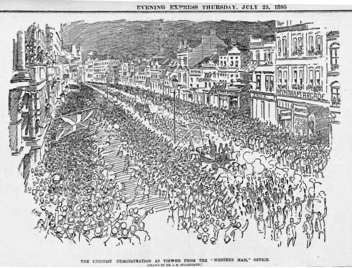 Schwarze und weiße Zeichnung einer Menge, die eine von Gebäuden gesäumte Straße entlanggeht, mit Text oben und unten, der lautet: "Die Unionistendemonstration, wie sie vom Western Mail Office aus zu sehen ist."