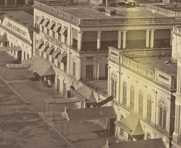 Schwaräweises Foto einer Straße mit Gebäuden, Fenstern, Säulen, Namensschildern, Hütten und Masten.