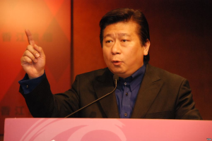 Ein Mann im Anzug und Krawatte hölt eine Rede an einem Rednerpult mit Mikrofon und sieht ernst aus.