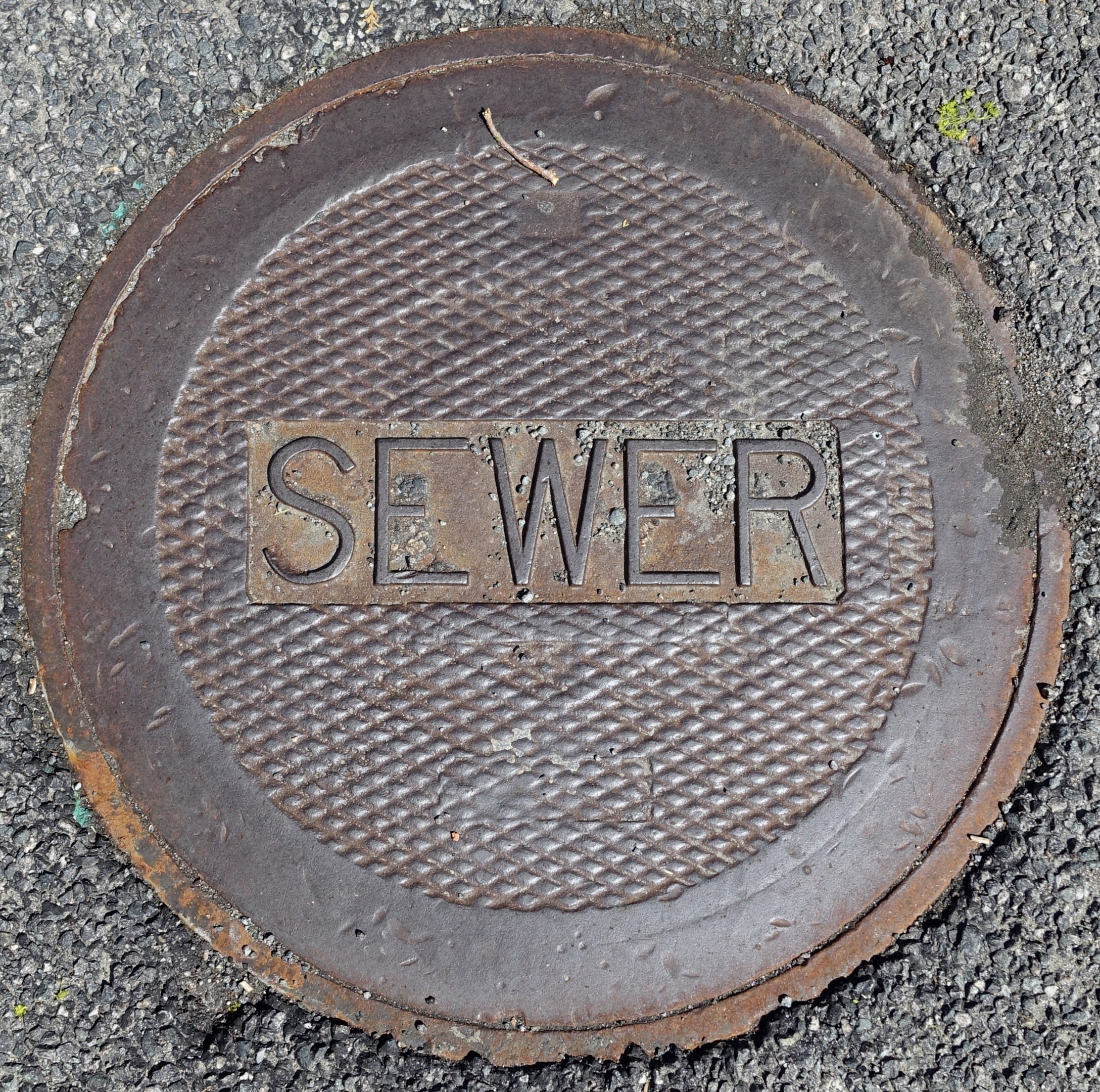 Metallschachtdeckel auf der Straße mit der Aufschrift "Kanal"