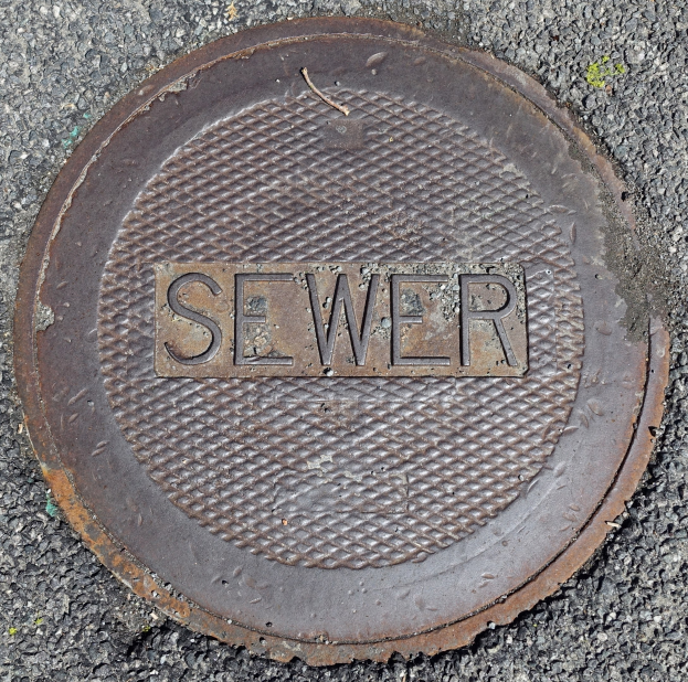 Metallschachtdeckel auf der Straße mit der Aufschrift "Kanal"