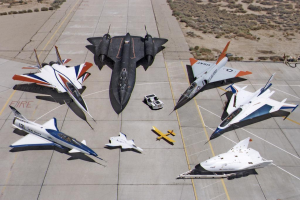 Ein Jet-Flug ist im Bildzentrum zu sehen, darunter eine Landebahn und Büsche im Hintergrund.