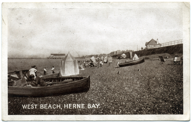 Schwarzes und weißes Foto von Menschen am Weststrand in Herne Bay mit Booten im Vordergrund, Häusern und einem Zaun im Hintergrund und Text unten.
