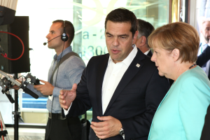 Bundeskanzlerin Angela Merkel und Bundespräsident Joachim Gauck stehen vor einer Glaswand mit einem Vorhang im Hintergrund, beide tragen Anzüge und Mikrofone.