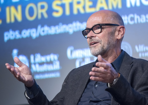 Steve Ballmer, Gründer und CEO von PBS, spricht in ein Mikrofon vor einem Bildschirm mit Text.