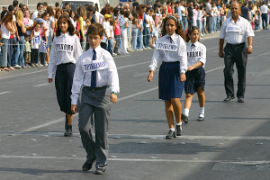 Eine Gruppe von Menschen, die auf einer Straße laufen, mit Abzeichen auf ihren Hemden, umgeben von einer großen Menge.