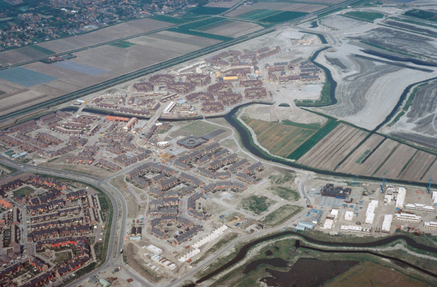 Luftaufnahme einer Stadt mit dichtem Baumbestand, Straßen, Feldern, Bäumen und einem zentralen Reservoir, das von städtischen Gebieten umgeben ist.