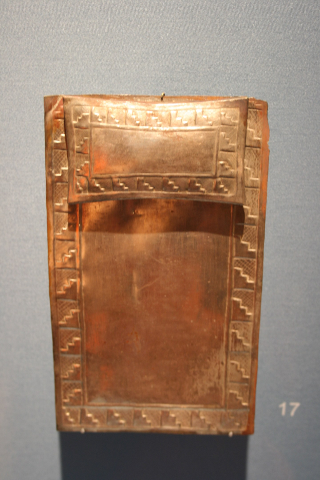 Kupferplatte mit detaillierten Designs in einem Museum ausgestellt, mit einer Wand und einer Zahl im Hintergrund.