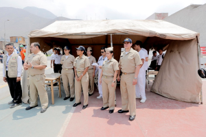 Polizisten und -polizistinnen vor einem Zelt mit Bergen im Hintergrund.