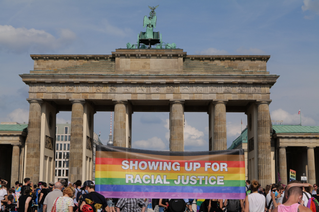 Eine Gruppe von Menschen steht vor dem Brandenburger Tor in Berlin, Deutschland, mit einer Tafel, auf der "Rassengerechtigkeit" steht.