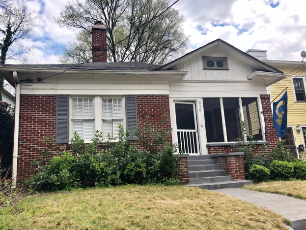 Ein Backsteinhaus mit weißen Fensterläden und einer Flagge, umgeben von Pflanzen, Gras, einem Weg, Bäumen, Drähten und einem bewölkten Himmel, befindet sich an 030 E Main St, Nashville, TN 37211 und ist unter der Liste ID 29058910 zu mieten.