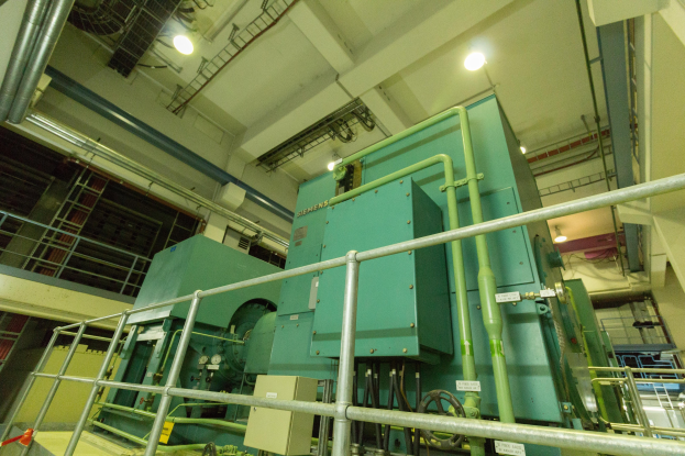 Eine große industrielle Wärmetauschermaschine in einem Gebäude, umgeben von Geländern, Rohren, Lampen und anderer Ausrüstung.