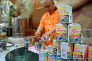 Vorgestellt: Flaschen im Vordergrund mit einem Mann dahinter, der mit Küchengeräten kocht.