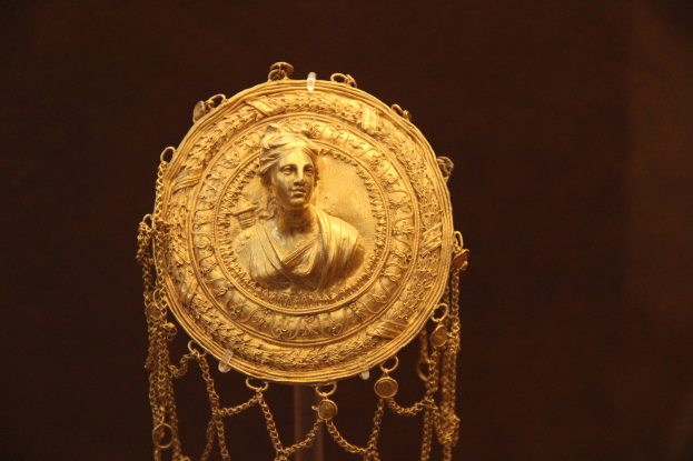 Goldene Medaille mit einer Frauengesicht, auf dunklem Hintergrund mit luxuriösen Details.