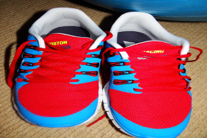 Ein Paar roter und blauer Schuhe mit Text darauf, positioniert vor einem unbestimmten Objekt.