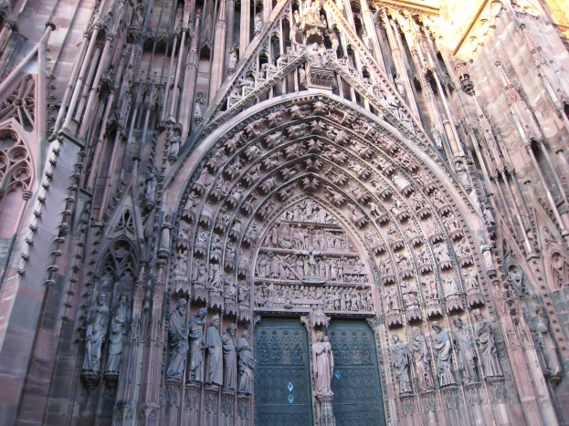 Der Eingang zum Kölner Dom in Köln, Deutschland, mit detaillierten Schnitzereien, Skulpturen und einer großen Tür unten.