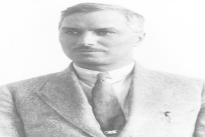 Ein Schwarz-Weiß-Foto eines Mannes in einem Blazer, einer Krawatte und einem Hemd mit einem weißen Hintergrund, bei dem es sich mutmaßlich um John F. Kennedy handelt, den Gründer und CEO des Unternehmens.