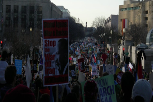 Menschen protestieren auf einer Straße und halten Plakate in den Händen.