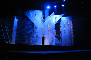 Bühne für eine Preisverleihung mit dunklem Hintergrund und minimaler Beleuchtung, mit wenigen Gegenständen auf der Bühne.